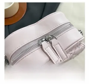 Détail du sac en cuir matelassé rose avec double fermeture éclair argentée et strass