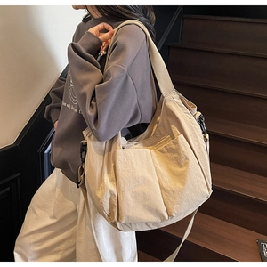 Detail of beige utility crossbody bag featuring spacious pockets and wide strap