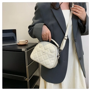 Close-up of quilted cream crossbody bag with textured leather and metal hardware detail