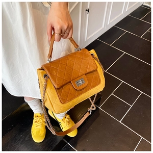 Detail of yellow quilted crossbody bag with brown leather flap and silver turn-lock