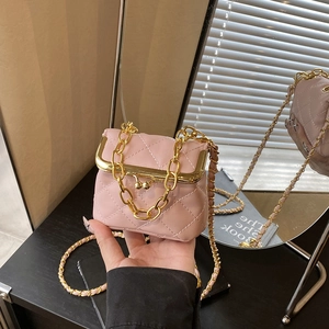Pink quilted mini crossbody bag with gold kiss lock and chain strap on a vanity table