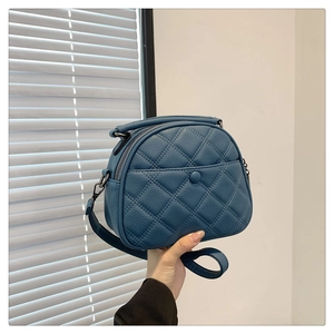 Detail of blue quilted leather shoulder bag with circular magnetic buckle and zipper