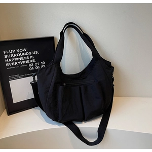 Close-up of large black nylon shoulder bag with functional multi-pockets and fabric strap