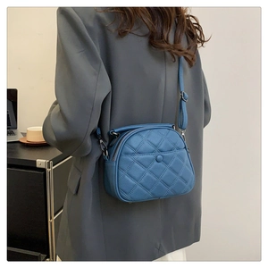 Detail view of quilted blue leather shoulder bag with double zippers and adjustable strap