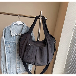 Detailed view of black wrinkled nylon tote bag with zipper pockets hanging on a rack
