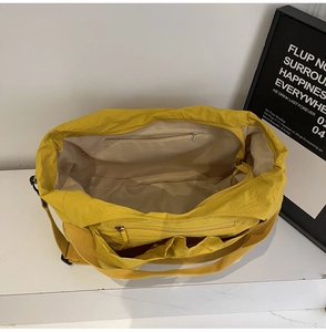 Detailed interior of yellow nylon tote bag with zipper pockets and light beige lining