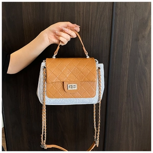 Detail of silver twist lock and quilted brown flap on denim contrast shoulder bag