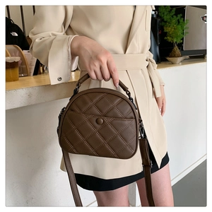 Detail of coffee brown quilted crossbody bag with top handle and lychee texture