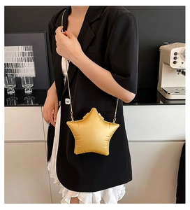 Detail of yellow star-shaped acrylic crossbody bag with gold chain strap on model