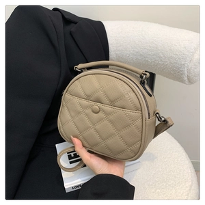 Macro view of beige quilted lychee grain faux leather shoulder bag with curved top handle