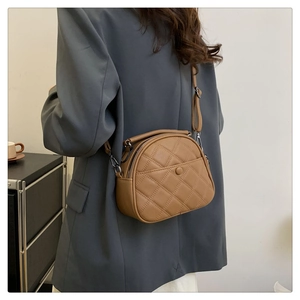 Rear view of brown quilted crossbody bag worn over a gray blazer for styling