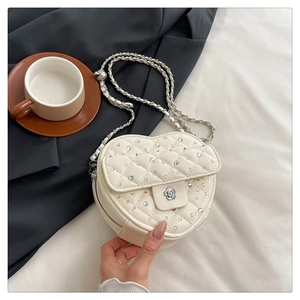 Détail du sac coeur matelassé crème avec strass et boucle en fleur argentée