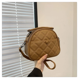 Close-up of brown quilted leather crossbody bag with top handle and dark hardware
