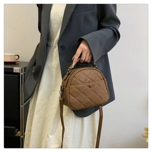 Detail of a brown quilted half-moon shoulder bag showing diamond stitching and top handle