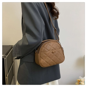 Close-up of brown quilted leather crossbody bag with adjustable strap and front pocket