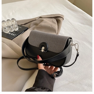 Détail d'un sac à main minimaliste en cuir noir avec rabat gris texturé et fermoir argenté