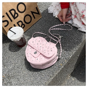 Détail d'un sac cœur rose matelassé avec accents de diamants et bandoulière en chaîne