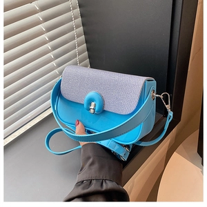 Détail du sac boîte bleu clair avec rabat tissé gris et fermoir métallique circulaire