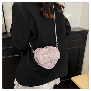 Détail du sac à main rose en forme de cœur avec strass matelassés et boucle camélia
