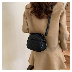 Close-up of a black quilted leather crossbody bag with adjustable strap worn by model