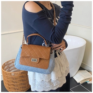 Close-up of quilted brown leather and blue denim patchwork bag with chain strap