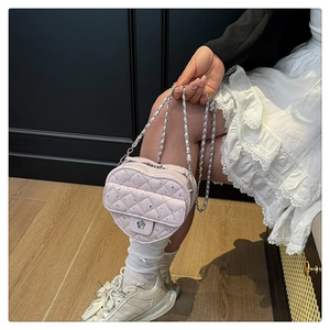 Détail du sac matelassé rose en forme de cœur avec cristaux et fermoir camélia