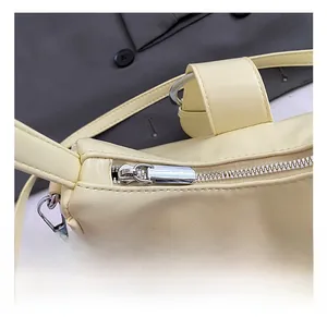 Close-up of premium cream leather bag showing silver metal zipper and buckle detail