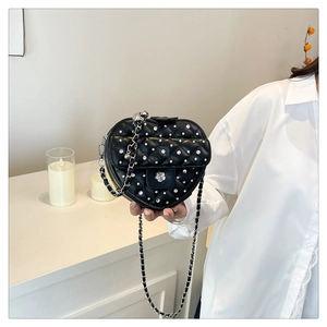 Détail du sac matelassé en forme de cœur avec strass brillants et boucle camélia