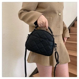 Close-up of black quilted rhombus crossbody bag with stylish top handle and front flap pocket