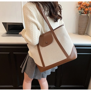 Détail du sac cabas en toile et cuir montrant les finitions et le design bicolore chic