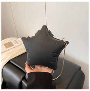 Detail of a star-shaped black crossbody bag with padded texture and gold chain strap