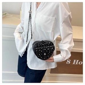 Détail du sac matelassé noir en forme de cœur avec rivets en strass et bandoulière chaîne
