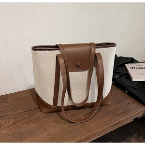 Détail du sac cabas en toile vintage avec finitions en cuir brun et fermoir aimanté