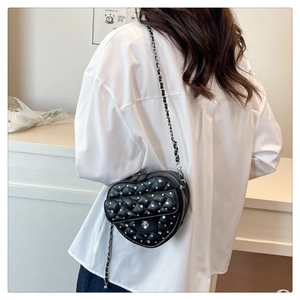 Détail du sac matelassé en forme de cœur avec accents de diamants et bandoulière chaîne