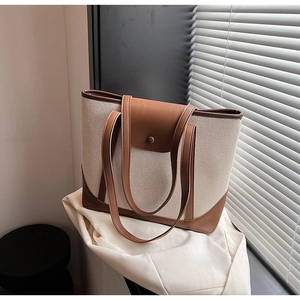 Détail du grand sac cabas en toile beige avec finitions en cuir marron et boucle en métal