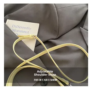 Close-up of bright yellow leather adjustable shoulder strap with silver metal buckle detail