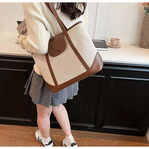 Détail d'un grand sac cabas vintage en toile avec finitions en cuir marron sur un mannequin
