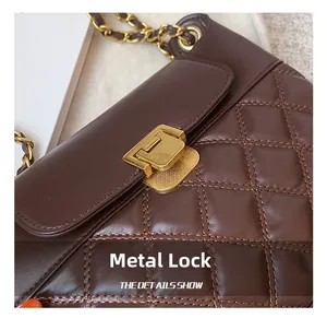 Detail einer dunkelbraunen Stepptasche mit hochwertigem goldenem Rechteck-Drehverschluss