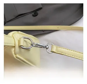 Close-up of the silver metal swivel hook and cream PU leather shoulder strap connector