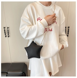 Detail of star-shaped crossbody bag with gold chain strap on a white sweatshirt