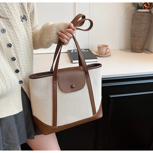 Détail du sac cabas en toile et cuir marron avec fermeture à boucle sur un bureau