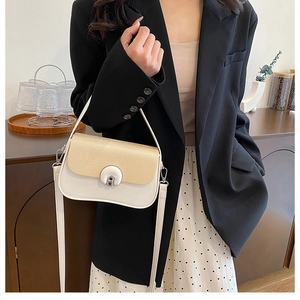 Détail d'un sac bandoulière minimaliste en cuir crème avec rabat en paille tressée