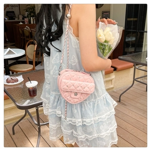 Détail du sac matelassé rose en forme de cœur avec strass et boucle en métal fleuri