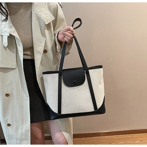 Détail d'un grand sac cabas bicolore en toile beige avec des finitions en cuir noir