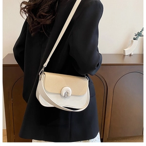 Détail d'un sac à bandoulière bicolore élégant avec coutures en cuir et rabat tissé
