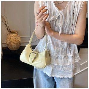 Detail of light yellow crescent underarm bag featuring a silver oval metal buckle clasp