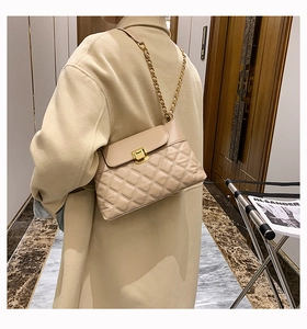 Detail einer beigen Stepptasche mit goldener Kette, von einem Model sanft getragen