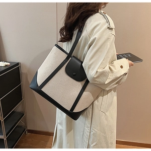 Détail d'un grand sac cabas en toile avec bordures en cuir noir et fermoir magnétique