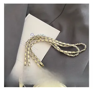 Detail of light yellow quilted bag with silver metal chain strap on gray blazer suit