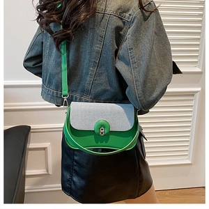 Détail du sac selle en cuir vert avec rabat rayé et fermoir rotatif sur un mannequin